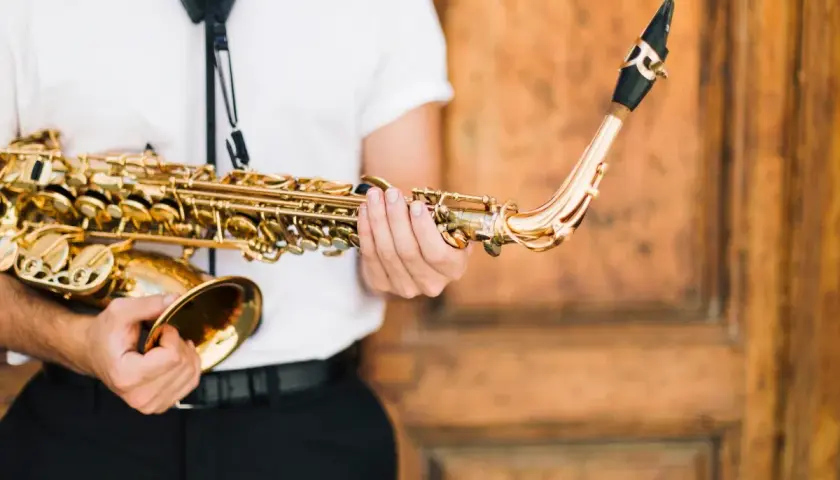 Un musicien tient un saxophone doré, prêt à apprendre cet instrument.