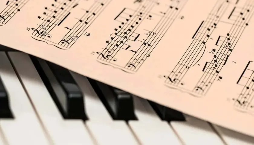 Partition de musique posée sur un clavier de piano. Les notes semblent prêtes à être jouées, une mélodie en attente de la touche de la diese.