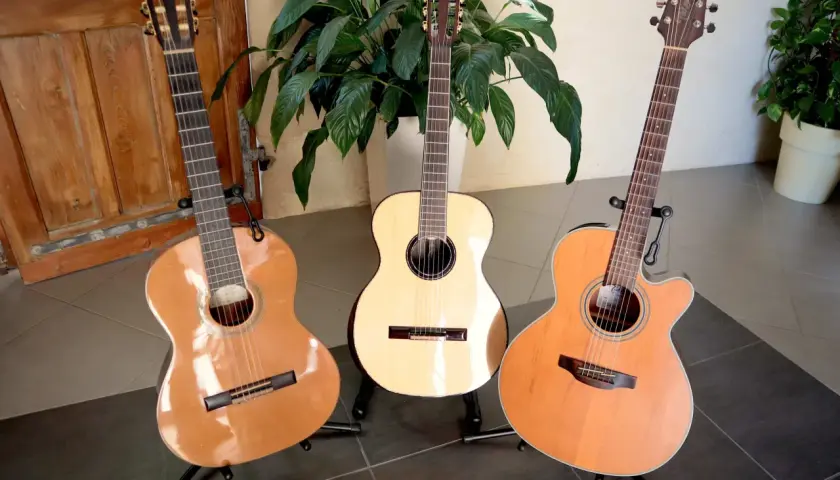 Trois guitares acoustiques sur des pieds, dont une avec une étiquette indiquant une marque de guitare.