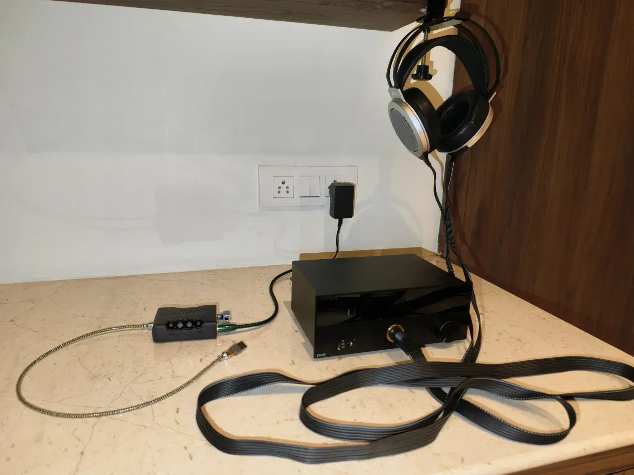 Casque audio suspendu, avec un pré ampli et un ampli audio noirs sur un bureau.