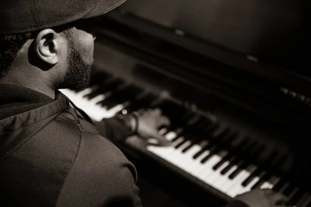 Un pianiste concentré joue un accord au piano, sa main effleurant les touches.