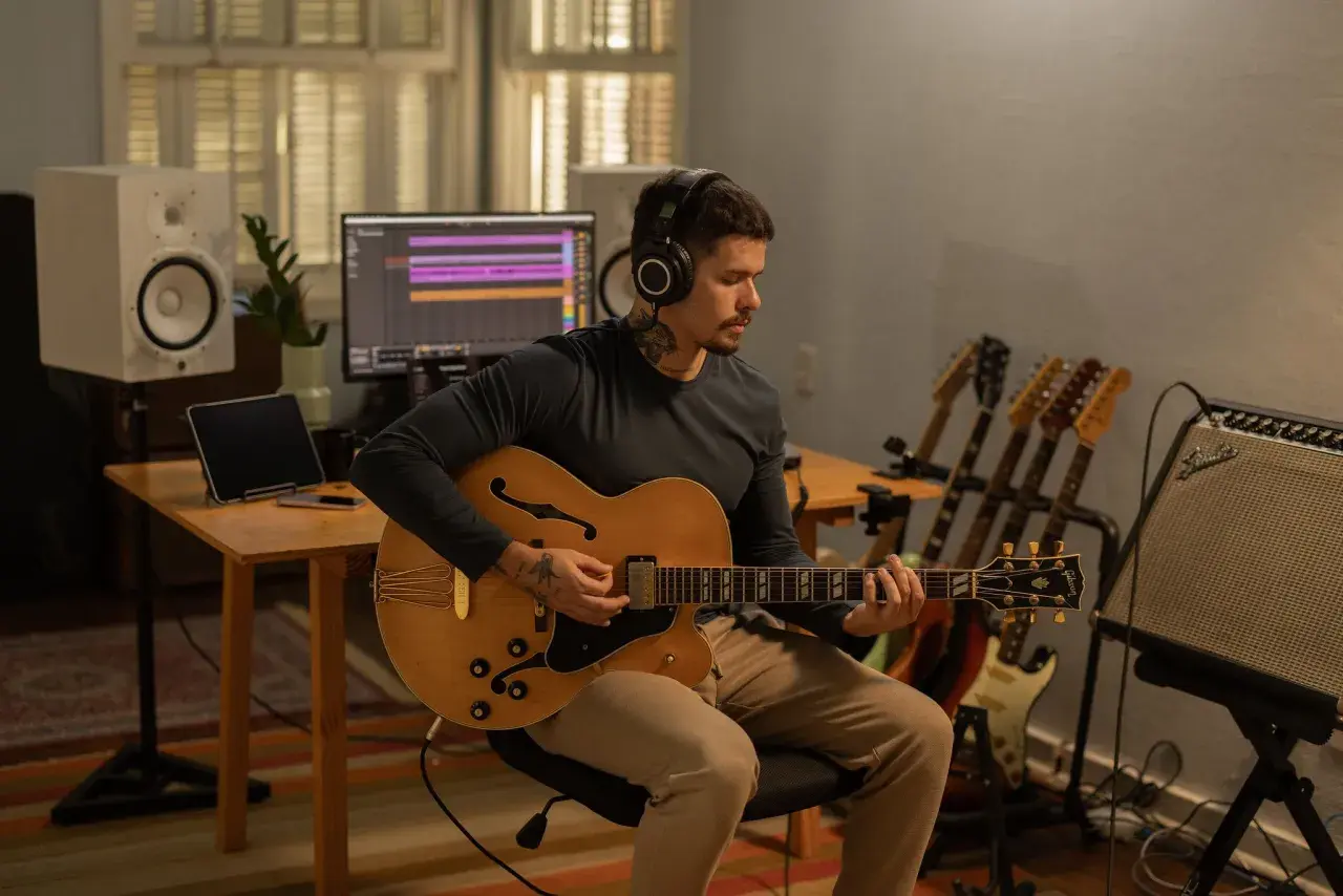 Un musicien concentré, casque sur les oreilles, joue d'une guitare acoustique dans un studio d'enregistrement. Il est prêt à enregistrer sa guitare acoustique.