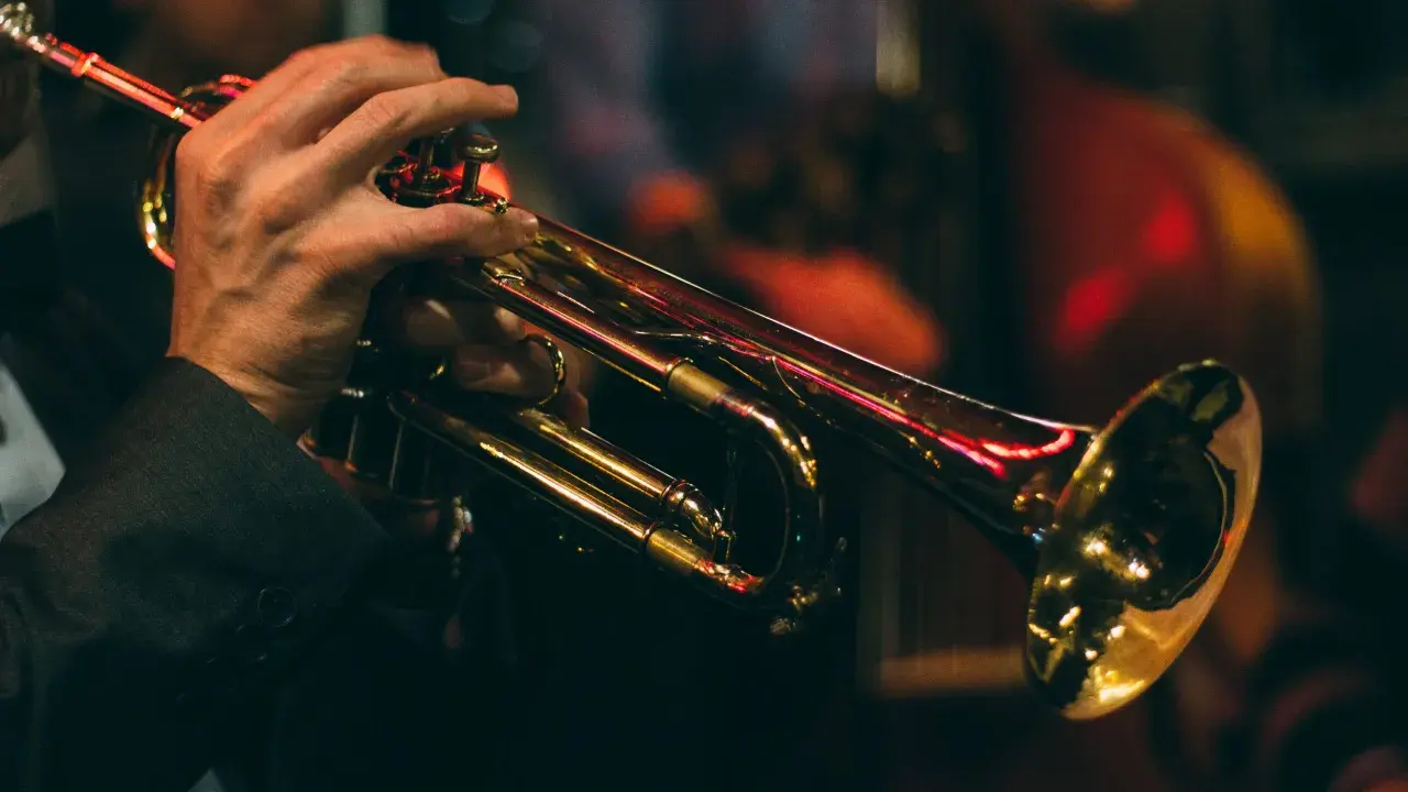Mains d'un musicien jouant de la trompette, illustrant le fonctionnement de l'instrument.