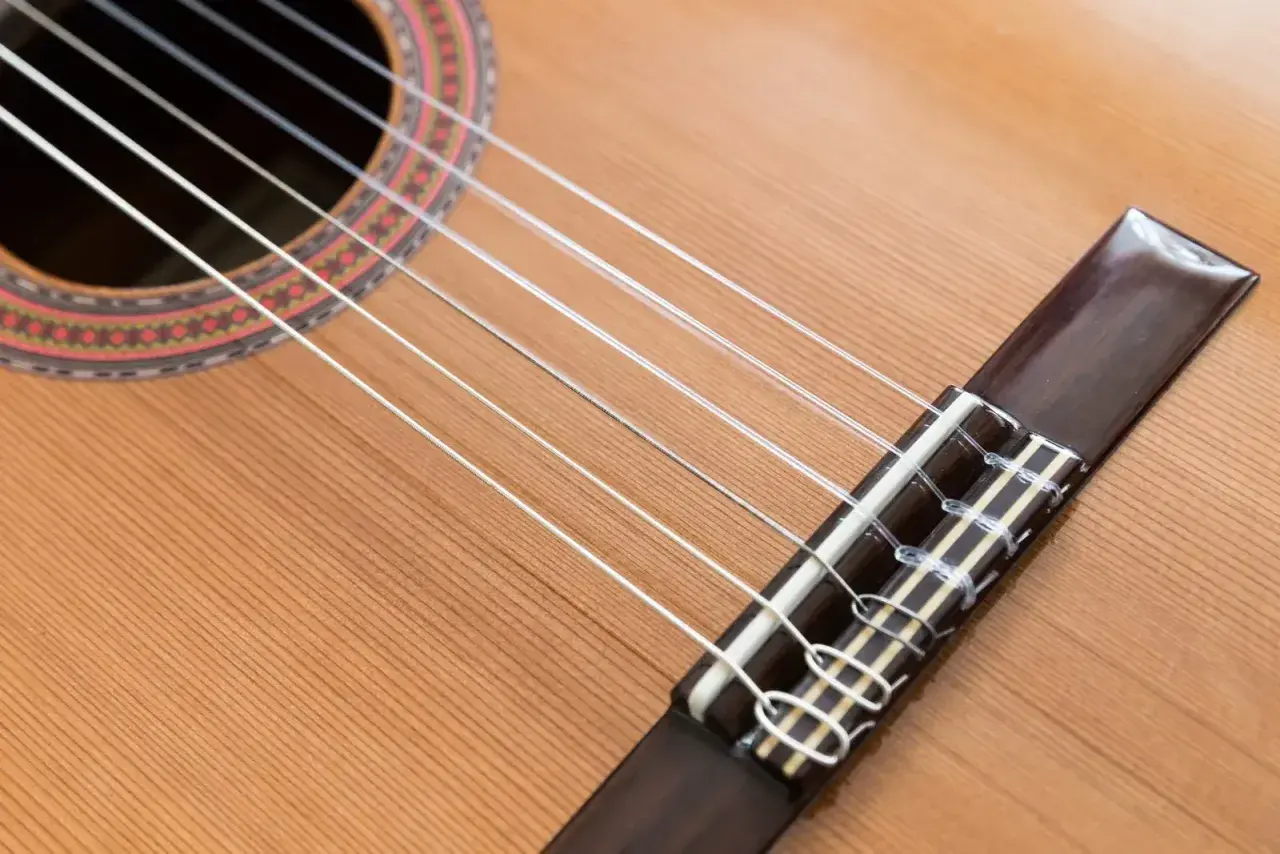 Guitare classique avec ses cordes en nylon, contrastant avec une guitare acoustique. Le bois clair et la rosace ornée invitent à la mélodie.