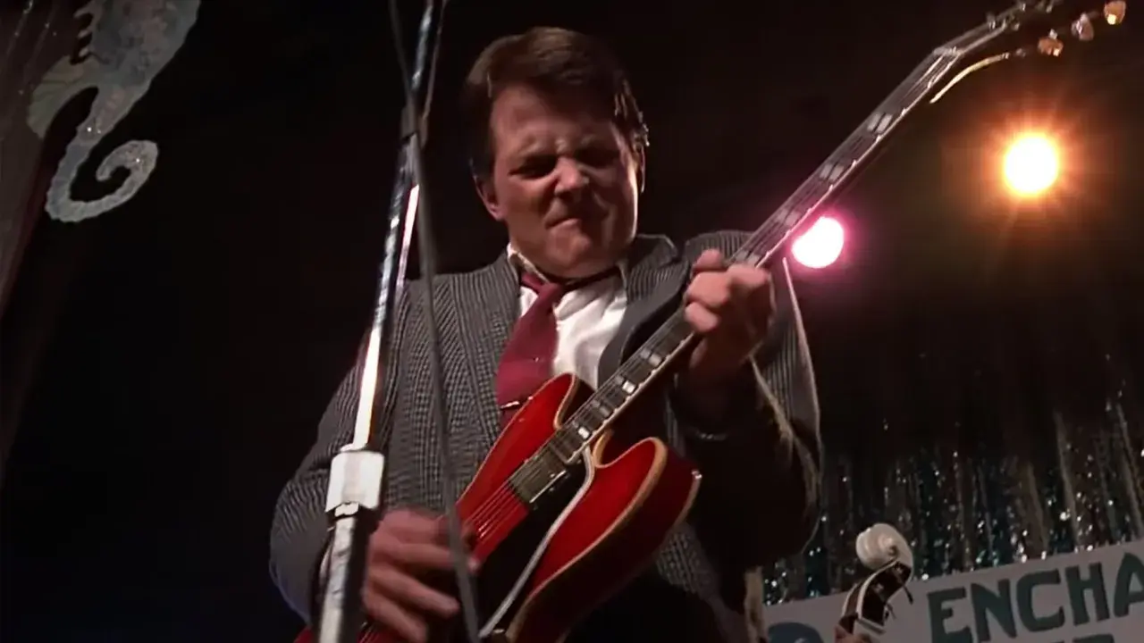 Marty McFly joue de sa guitare rouge emblématique sur scène, prêt à faire vibrer le public.