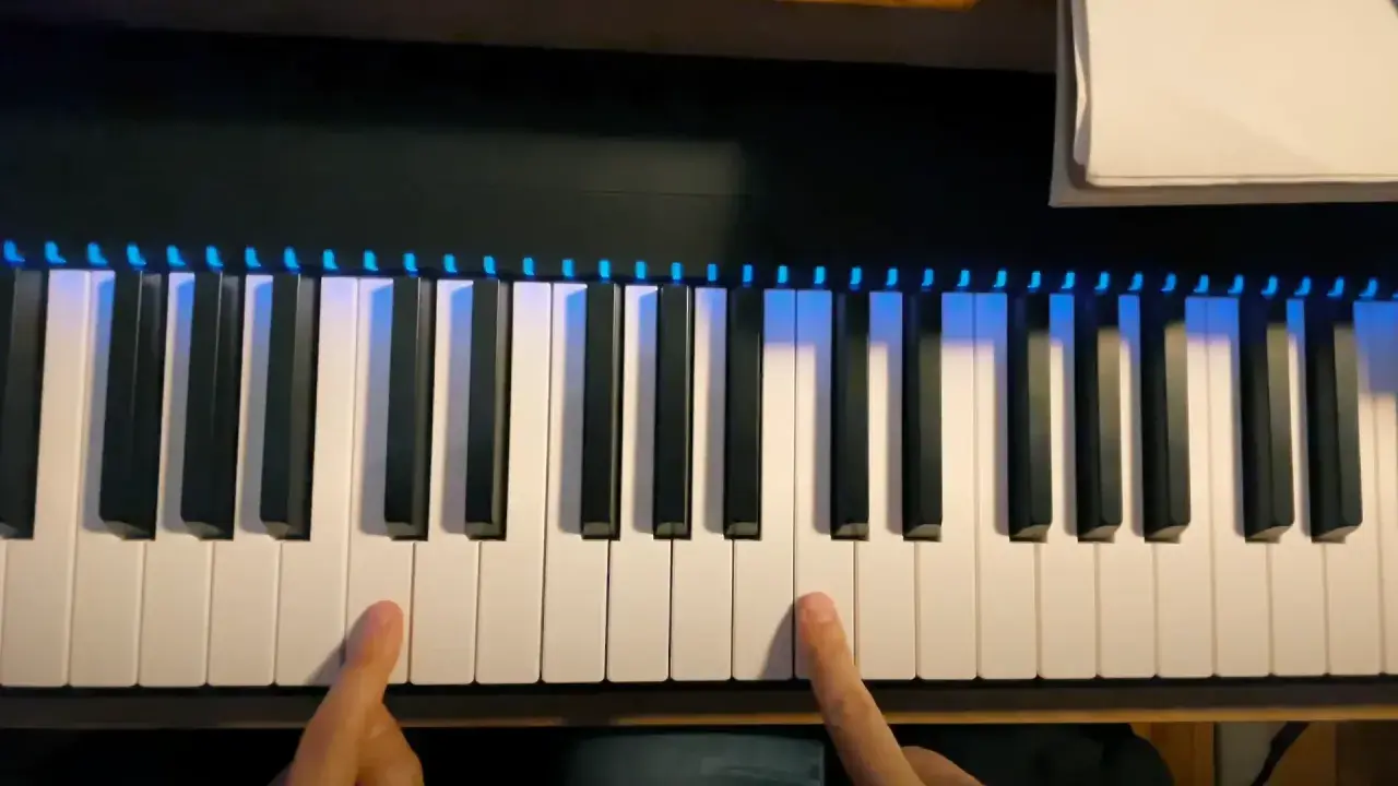Les doigts effleurent les touches d'un **dièse clavier** illuminé de bleu, prêt à jouer une mélodie.