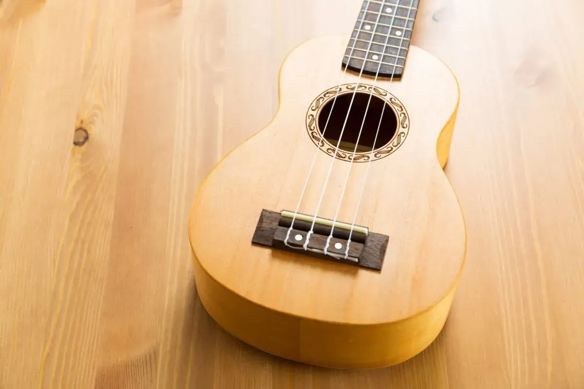 Un joli ukulélé en bois clair, prêt à jouer de la musique sur une table en bois.