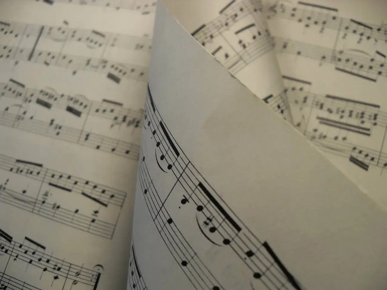 Feuilles de musique aux notes et portées, un dieze sigle se distingue sur une partition pliée.