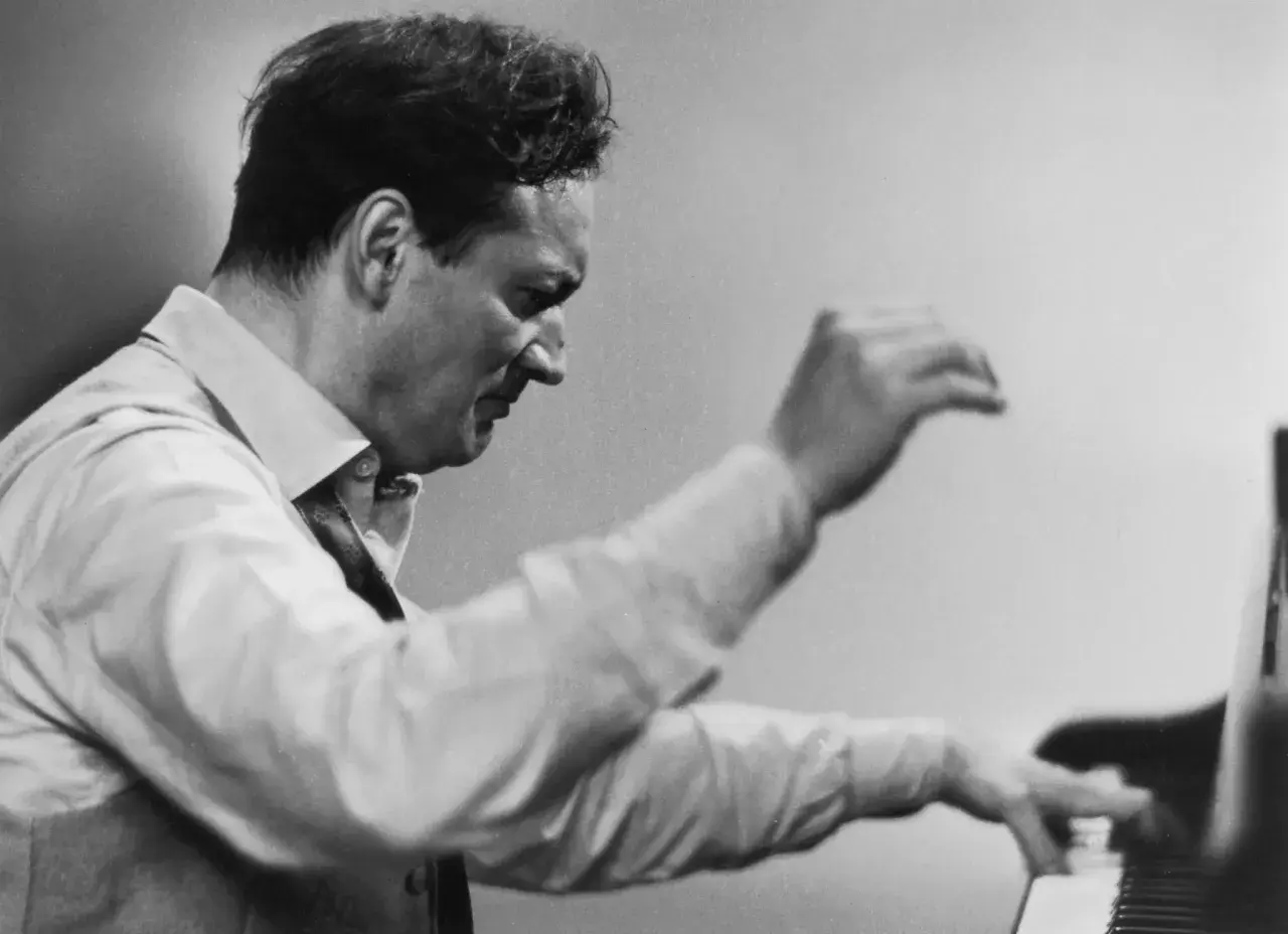 Un pianiste connu, le regard concentré, ses mains effleurent les touches du piano, capturant l'essence de la musique.