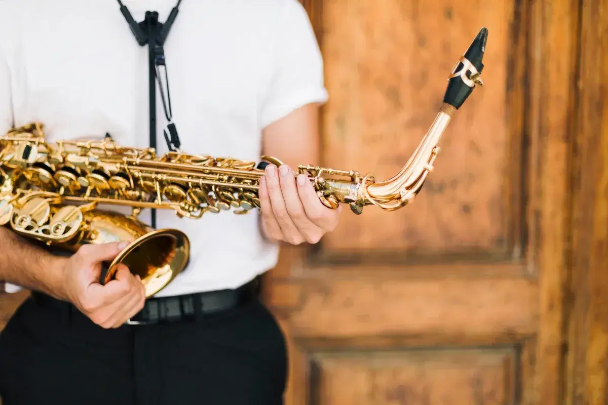 Un musicien tient un saxophone doré, prêt à apprendre cet instrument.