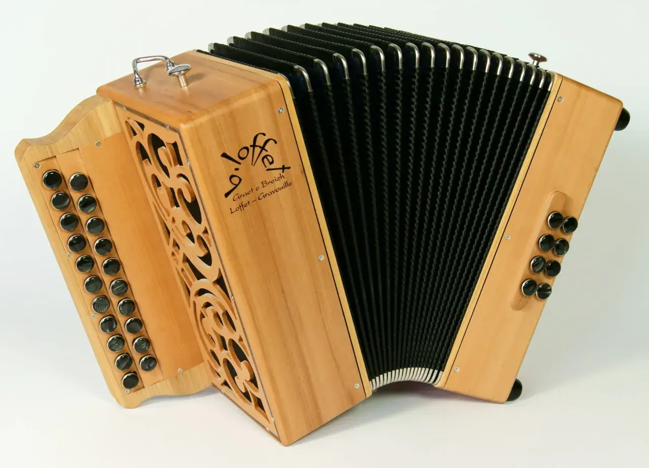 Un accordéon instrument à vent en bois clair, avec des boutons noirs et un soufflet noir. Le logo "Loffet" est visible.