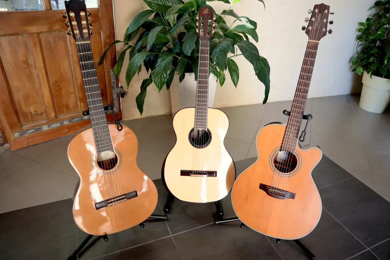 Trois guitares acoustiques sur des pieds, dont une avec une étiquette indiquant une marque de guitare.
