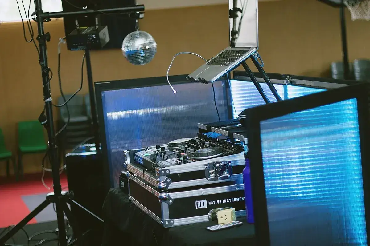Un booth DJ prêt pour la fête, avec platines, ordinateur portable et boule disco scintillante.