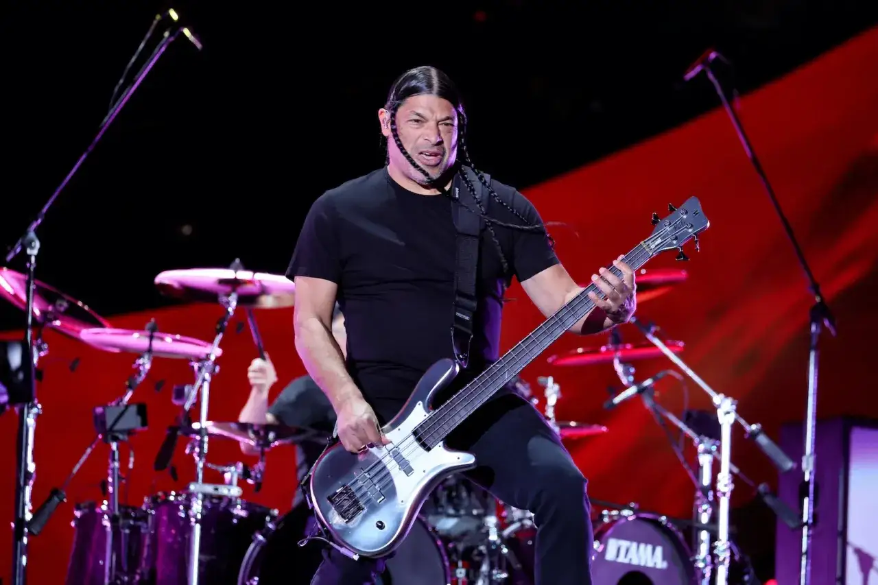 Robert Trujillo, bassiste de Metallica, en pleine performance, ses tresses noires dansant au rythme de la musique.