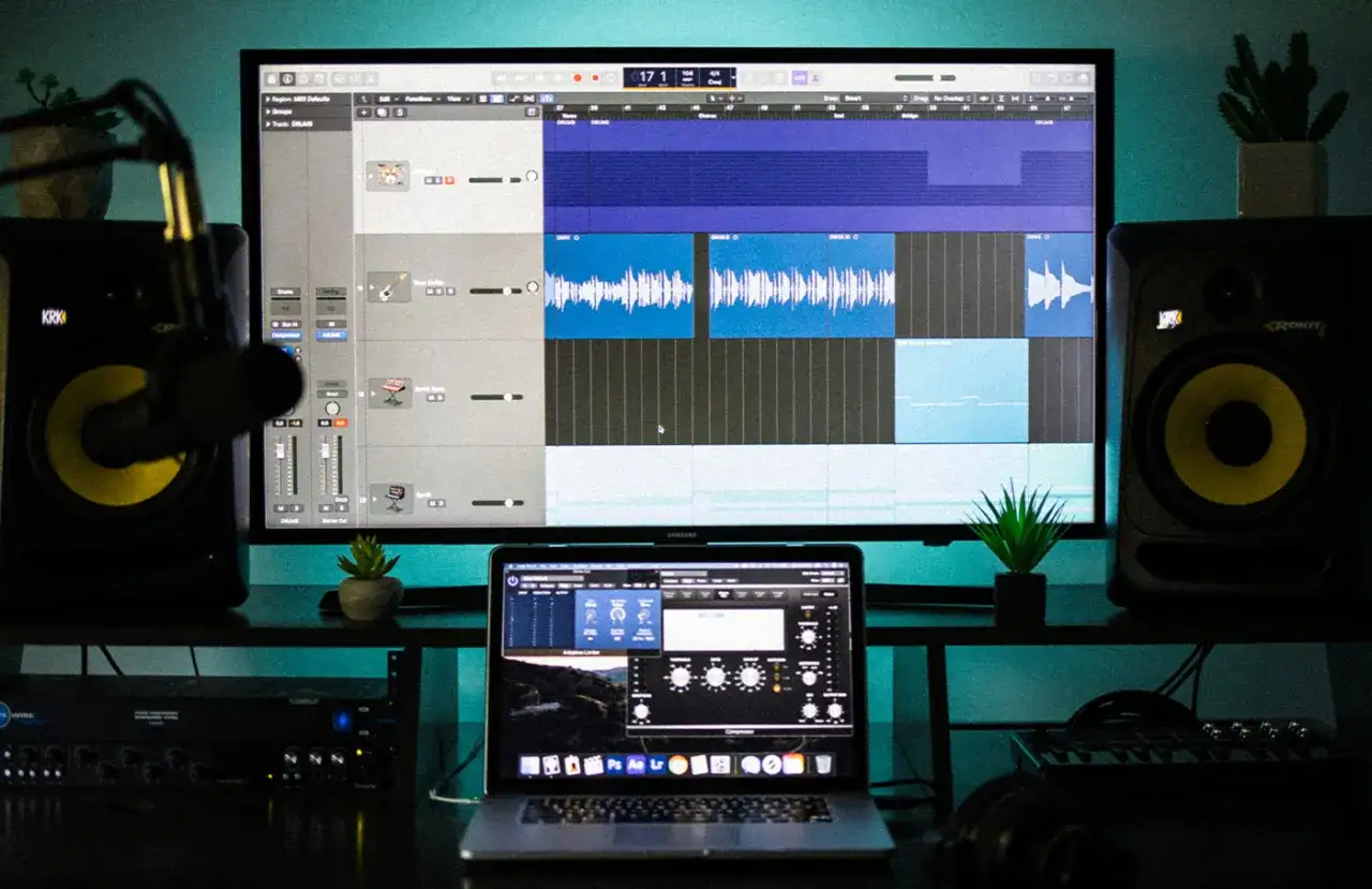 Studio d'enregistrement à domicile avec écran affichant un logiciel home studio, enceintes, microphone et ordinateur portable.