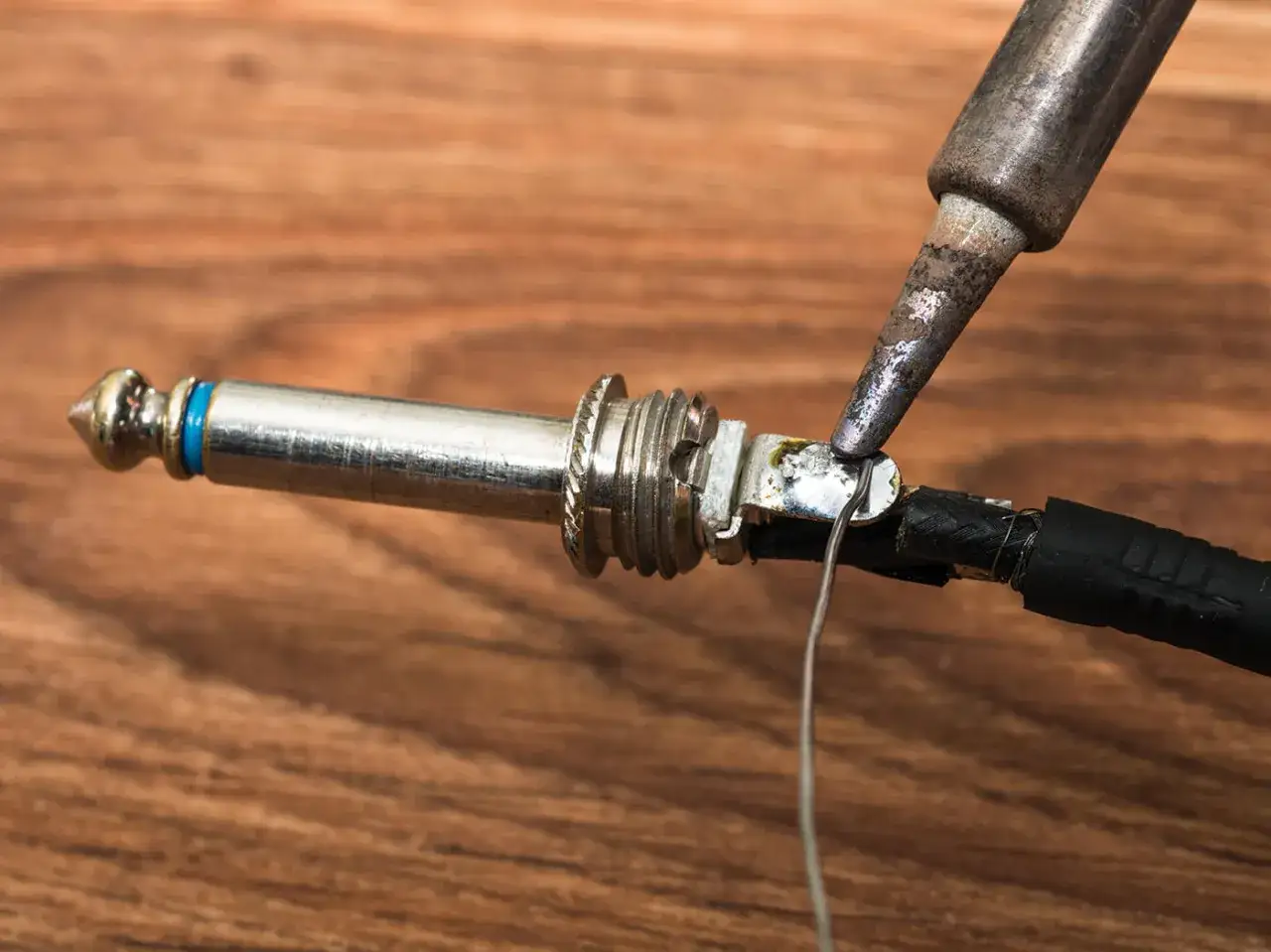 Réparation d'un problème de prise jack de guitare électrique. Un fer à souder est utilisé pour reconnecter un fil au connecteur.