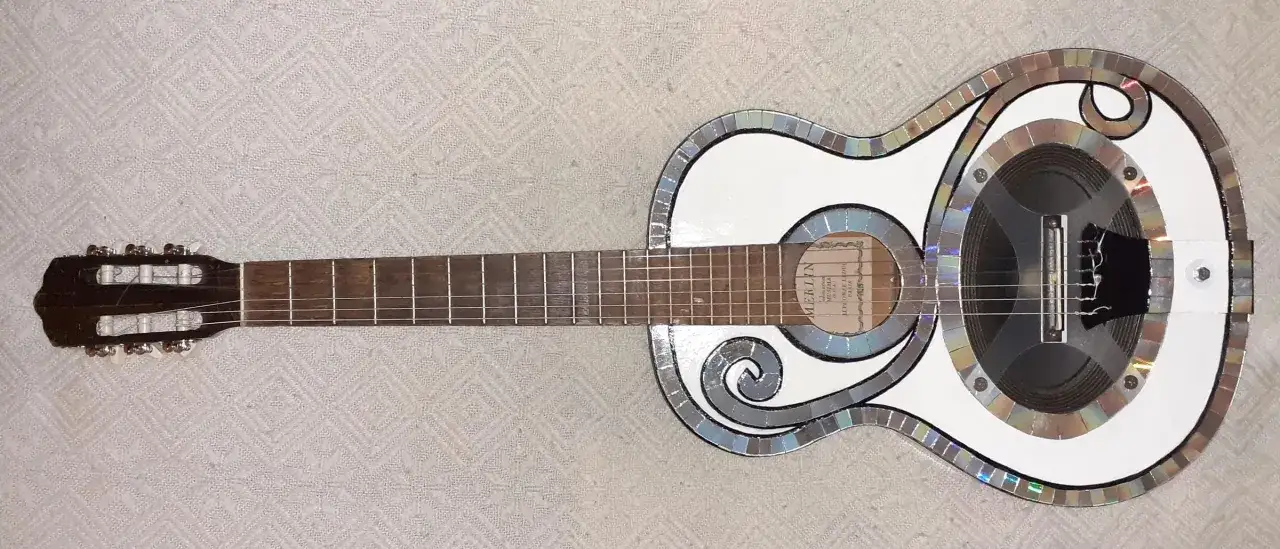 Guitare blanche d&eacute;cor&eacute;e de CD recycl&eacute;s, pr&ecirc;te &agrave; produire le son de la guitare.