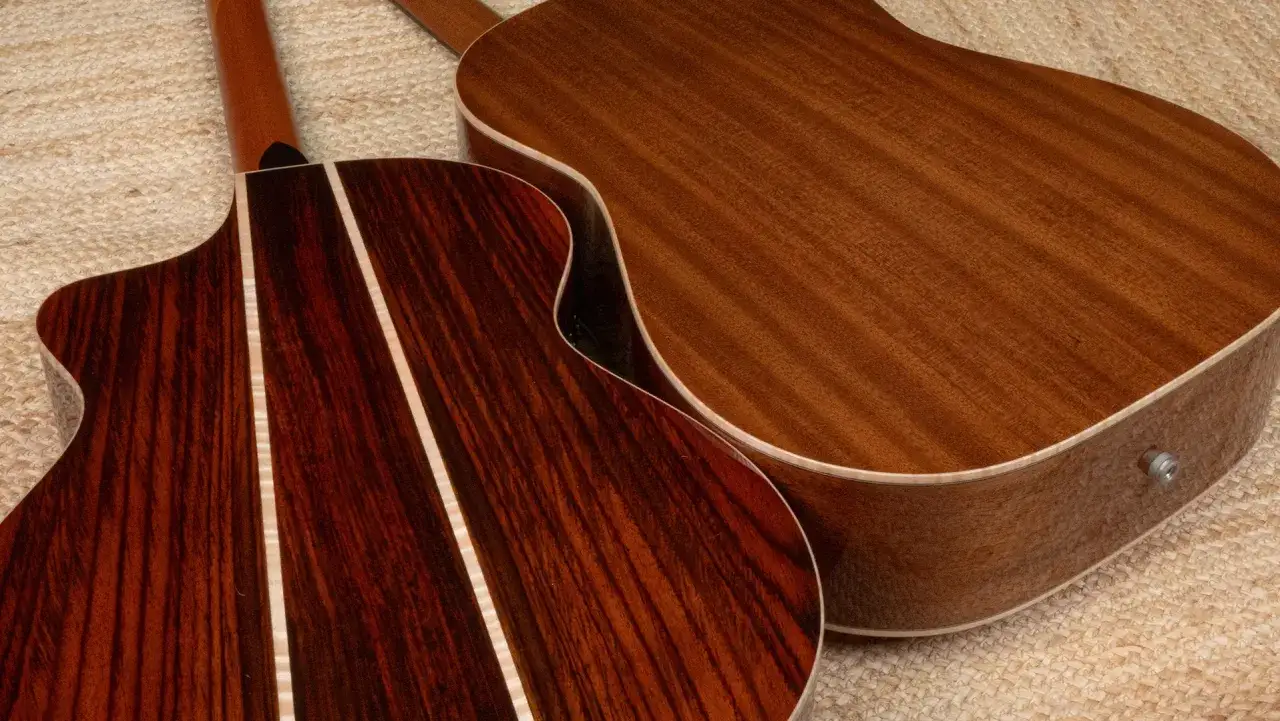 Deux guitares acoustiques, l'une avec un dos en palissandre aux rayures sombres et claires, l'autre en bois plus clair.