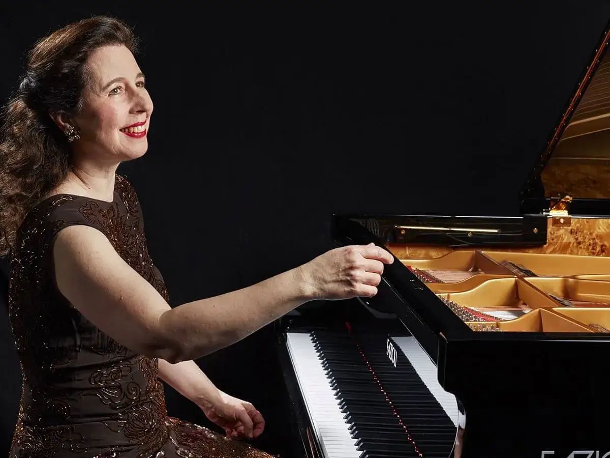 Une pianiste connue, souriante, s'appr&ecirc;te &agrave; jouer sur un magnifique piano &agrave; queue noir.