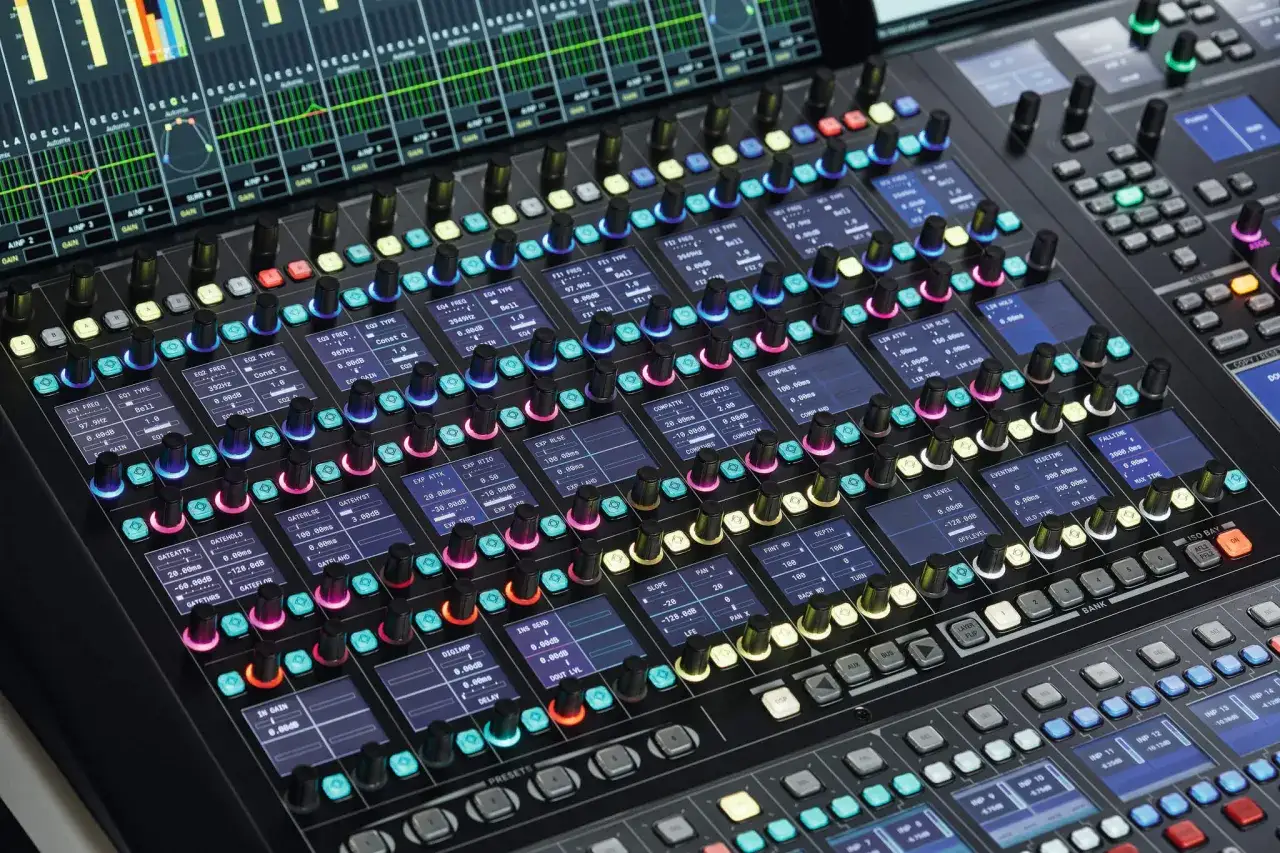 Console de mixage numérique avec écrans lumineux affichant les réglages des pistes et un mix bus central.