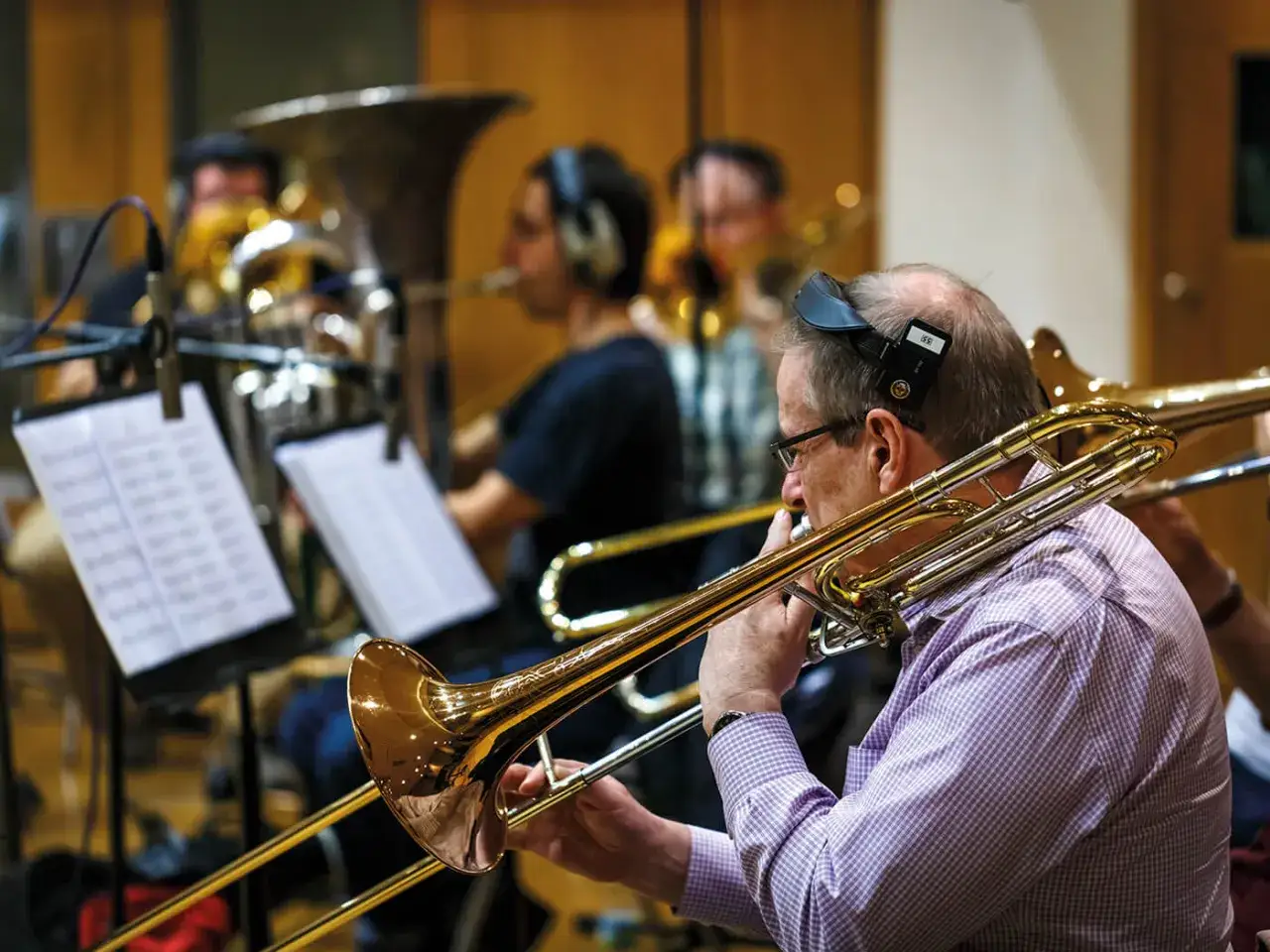 Un musicien joue du trombone, un instrument de musique de la famille des cuivres, dans un studio d'enregistrement.
