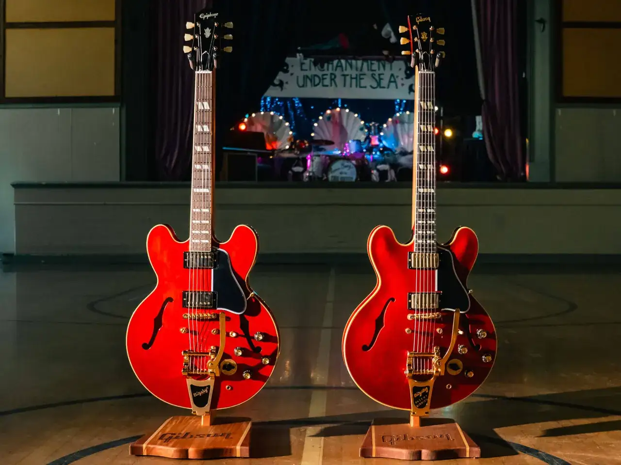 Deux guitares rouges, style Marty McFly, sur des supports en bois, devant une sc&egrave;ne de bal 