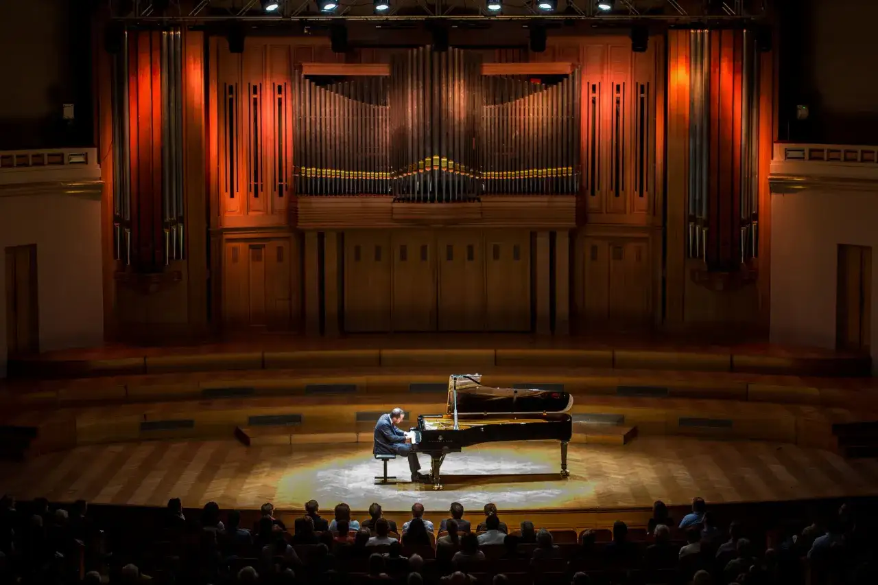 Un pianiste interprète une musique classique piano connue devant un orgue imposant. L'ambiance est solennelle.