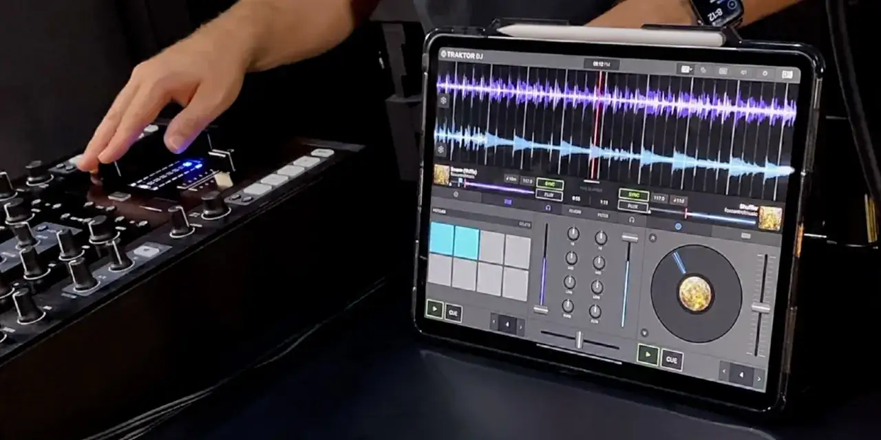 Un DJ mixe avec un iPad affichant Traktor DJ, contrôlant la musique via une table de mixage. L'interface tactile de l'iPad sert de contrôleur midi.